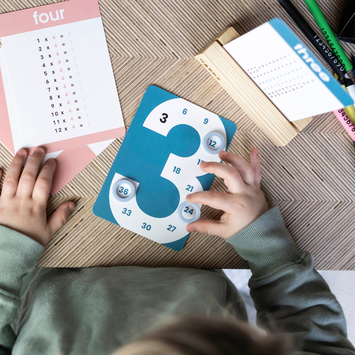 A child placing counters on the numbers of a Times Tables skip-counting card